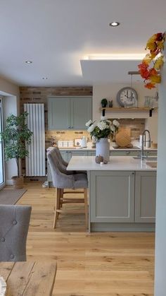 an open kitchen and dining room with wood flooring in the living area, along with large windows