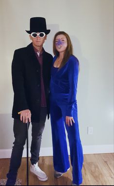 a man and woman are dressed up as elvis and the girl in blue is holding a cane