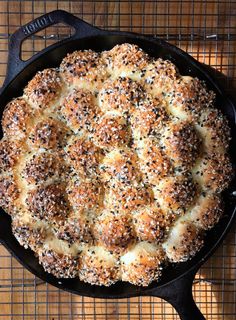 a cast iron skillet filled with bread on top of a wooden table next to a wire rack