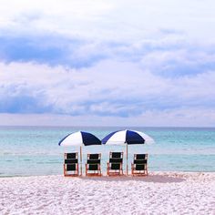 two beach chairs with umbrellas on the beach