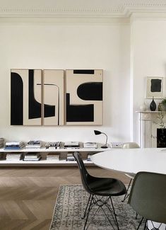 a living room filled with furniture and paintings on the wall above a table in front of a fire place