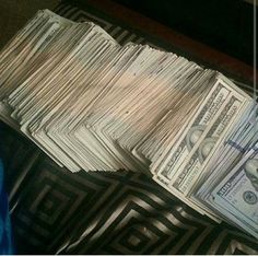 a pile of money sitting on top of a black and white floor next to a person's feet