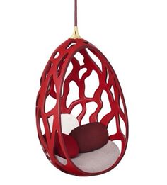 a red hanging chair with a white cushion and pillow in the shape of an egg