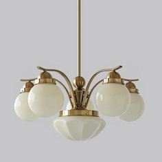 an antique brass chandelier with five white glass globes hanging from the ceiling