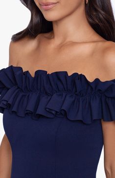 a woman wearing a blue off the shoulder dress