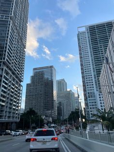 cars are driving down the street in front of tall buildings and high rise skyscrapers