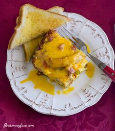 a white plate topped with an omelet covered in cheese next to a slice of bread