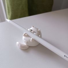 a white pencil with a cat figurine sticking out of it's end