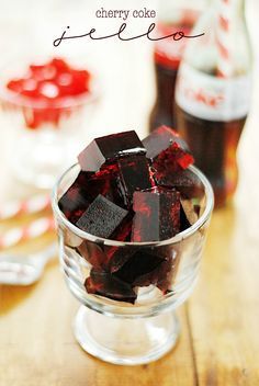 a glass bowl filled with red and black cubes on top of a wooden table