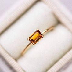 an engagement ring in a white box with a yellow stone on the top and bottom