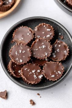 chocolates in a black bowl with sea salt on top and two bowls behind them