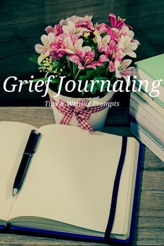 a notebook and pen sitting on top of a table next to some books with flowers in it