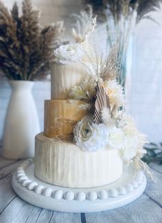 a three tiered cake with flowers and feathers on top