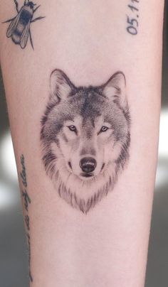 a tattoo on the leg of a woman with a wolf head and bees around her