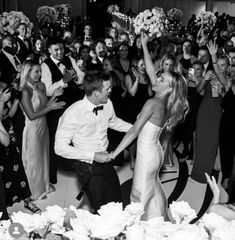 a man and woman dancing in front of a large group of people at a wedding