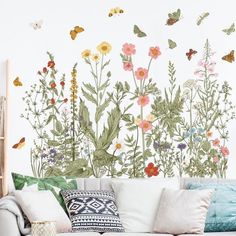 a living room filled with furniture and lots of colorful flowers on the wall behind it