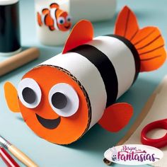 an orange and black fish made out of toilet paper next to some crafting supplies