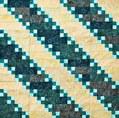 a green and yellow quilt with blue squares on the bottom, in front of a white background