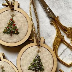 three cross stitch christmas tree ornaments with scissors