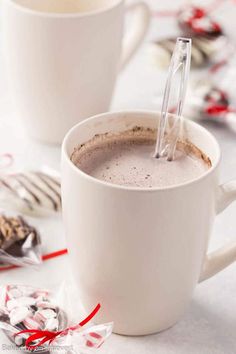 two white mugs filled with hot chocolate and candy