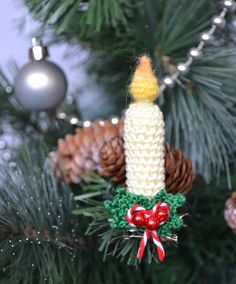 a crocheted candle ornament hanging from a christmas tree