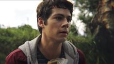 a young man is standing in front of a tree and looking off into the distance