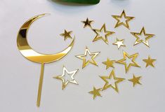 some gold stars and a crescent on a white table