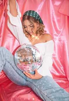 a woman sitting on the ground holding a disco ball