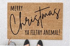 a door mat with the words merry christmas ya filthy animal on it and two pairs of shoes