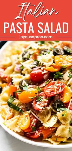 pasta salad with tomatoes, olives and cheese in a white bowl on top of a table