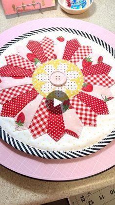 a pink plate with a patchwork flower on it next to a ruler and other crafting supplies