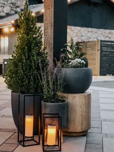 two lit candles sitting next to each other on top of a stone floored area