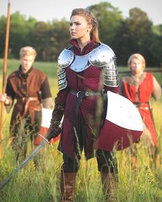 a group of people standing in a field next to each other wearing armor and holding swords