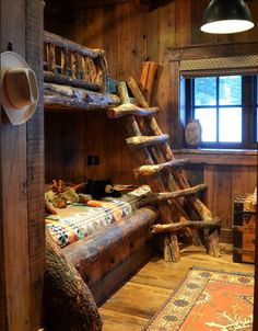 a bunk bed made out of logs in a room with wooden walls and flooring