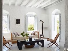 a living room filled with furniture and windows next to a white brick wall covered in arched doorways