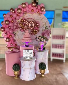 pink and gold decorations are on display in a room with white chairs, round tables and large balloons