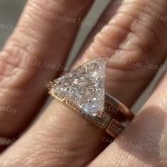 a woman's engagement ring with a triangle shaped diamond in the middle, on her finger