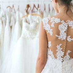 the back of a woman's dress in front of wedding gowns