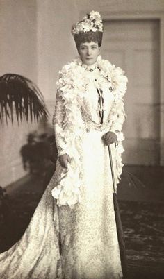 an old black and white photo of a woman in a dress with flowers on it