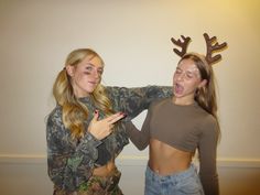 two young women dressed up as deer antlers, one pointing at the other's chest