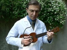 a man in a white lab coat is holding a ukulele and looking at it