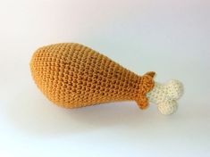 an orange crocheted object with a small white one in the middle on a white surface