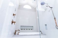 a bathroom with a glass shower door and two faucets on the side of the bathtub