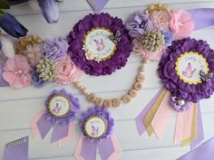 purple and pink flowers with name tags attached to them on a white table next to other items