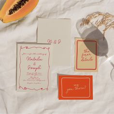 the wedding stationery is laid out on top of the table with fruit and paper