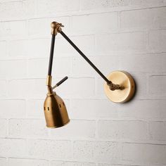 a wall mounted light on the side of a white brick wall next to a lamp