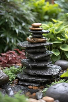 rocks stacked on top of each other with water running down them in front of some plants