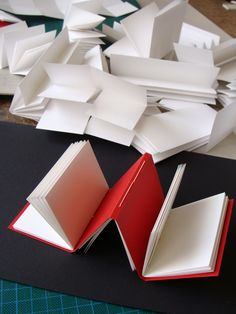 two open books sitting on top of a table next to folded up sheets of paper