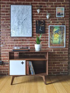 a wooden table sitting in front of a brick wall with pictures on the wall behind it