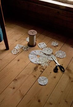 scissors and spools of thread sit on the floor next to some doily